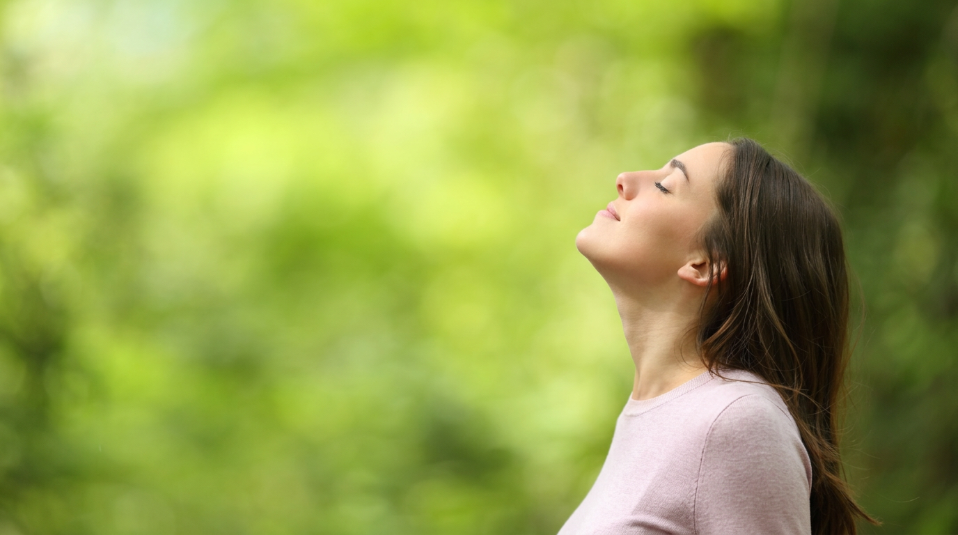 Mulher respirando tranquilamente em meio à natureza